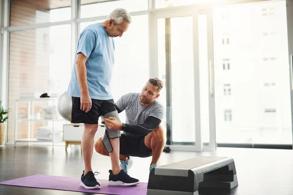 Stock image Lets get your body back to functioning 100. a young male physiotherapist assisting a senior patient in recovery