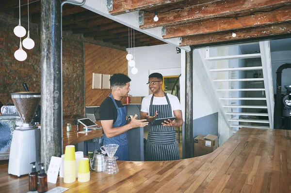 Stock image Collaborating to bring you awesome coffee. two young men using a digital tablet while working in a cafe