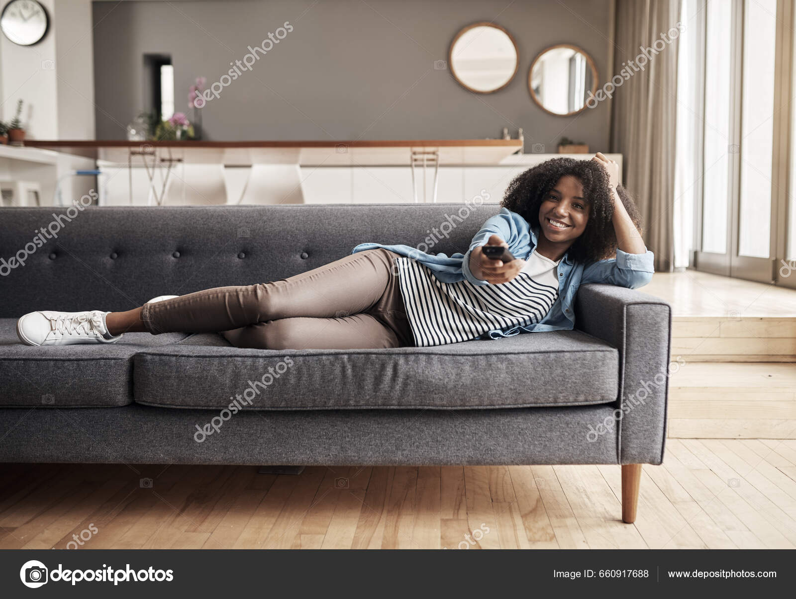 Garota feliz com telefone relaxa no sofá ou no sofá da sala