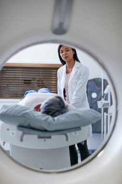 MR, doktor ve kadın makinede taramadan önce hastayı hastanede rahatlatır. Klinikteki radyoloji sağlık testinden önce yaşlı bir kadın ile tomografi, rahatlatıcı ve tıbbi uzmanlık.