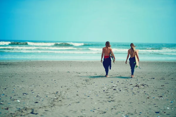 彼の心への道はサーフィンを通してです 若いカップルがサーフボードを持ってビーチを歩いていて — ストック写真