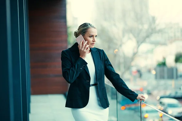 一个严肃的电话需要隐私 一个成熟的女商人 站在办公室的阳台上 用手机 — 图库照片