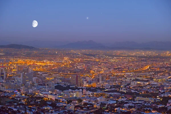 City, Cape Town and night view of building lights and architecture in the industrial urban town of South Africa. Late evening of outdoor scenery of moon or sky over buildings or cityscape structures.