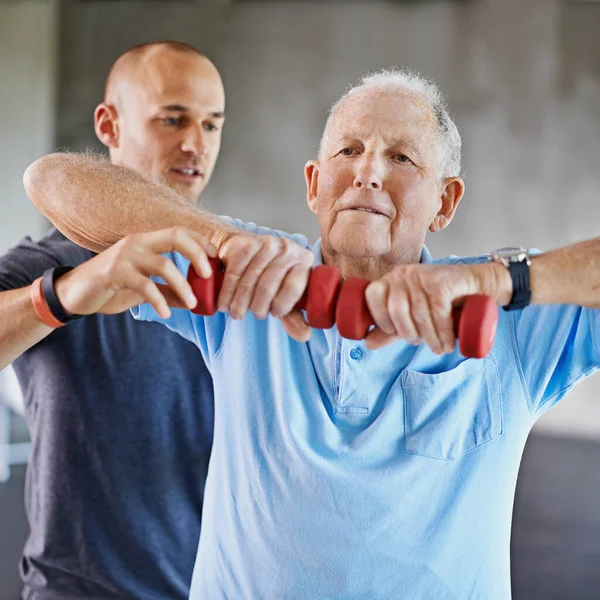 stock image Physiotherapist man, senior patient and weight training for health and wellness therapy in retirement. Healthcare, physio and workout for recovery with a dumbbell for medical care and elderly person.