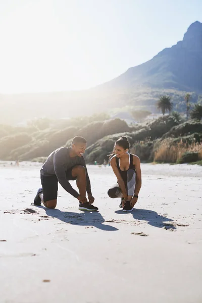 准备把他们的心挖出来一对年轻的运动型夫妇在海滩边跑步时把鞋带捆起来 — 图库照片