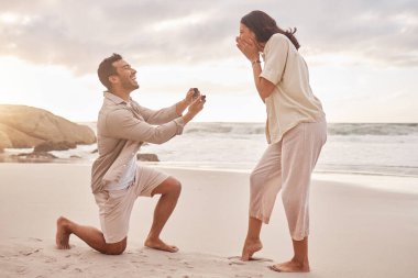 Couple, engagement proposal and surprise at beach with smile, happiness or love on vacation in sunset. Man, woman and ring with marriage offer by ocean with smile, excited face or together on holiday. clipart