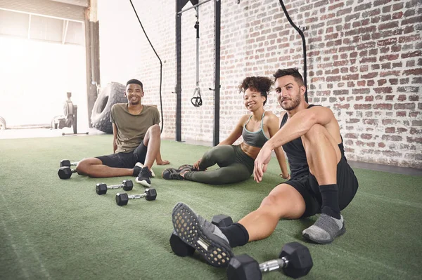 A fitness group makes you think twice about skipping gym. a fitness group resting after working out with dumbbells