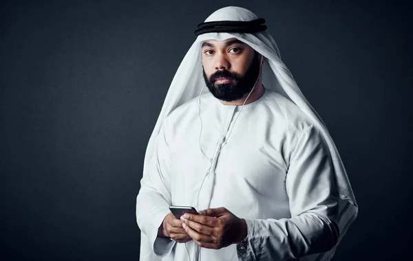 技術は伝統的な男を助ける 暗い背景を背景にポーズをとったイスラムの伝統的な服を着た若い男のスタジオショット — ストック写真