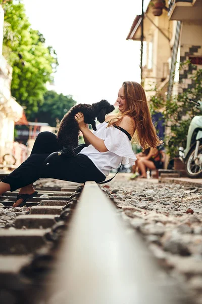 私は親友と旅行している 外国の都市を探検しながら犬と遊ぶ若い女性は — ストック写真