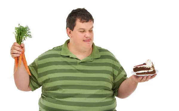 プラスサイズ 空腹の決定とニンジンとデザートの選択と男は食べ物について考えています 体重減少と栄養バランスのアイデアと健康とケーキの順序と男性モデル スタジオと白の背景 — ストック写真