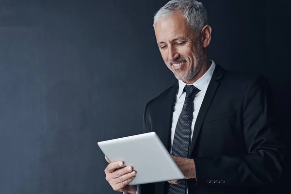 stock image Smart technology is a staple for the business savvy. Studio shot of a mature businessman using a digital tablet against a dark background