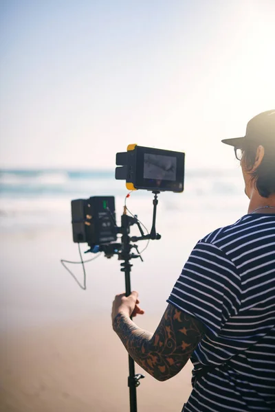 撮影はとてもうまくいっています 一日中ビーチの外で最先端のビデオカメラでシーンを撮影した焦点を当てた若い男のレビュー — ストック写真
