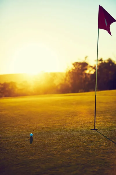 芝の上へ 空のコースにあるゴルフボールと旗は — ストック写真