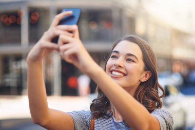 Şehirde selfie 'ler. Çekici bir genç kadın şehirde gününü geçirirken selfie çekiyor.