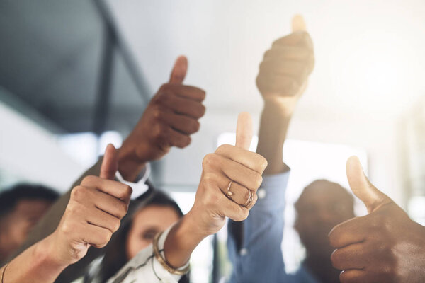 Wishing you all the best. Closeup shot of a group of businesspeople showing thumbs up in an office
