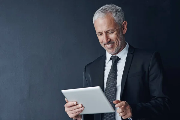 stock image Virtual assistants are great for busy executives. Studio shot of a mature businessman using a digital tablet against a dark background