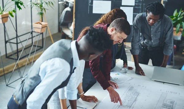 stock image I have an even better idea for this. a team of professionals working on blueprints in an office