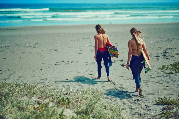 時間がまだ立っている場所にオフ 若いカップルがサーフボードを持ってビーチを歩いていて — ストック写真