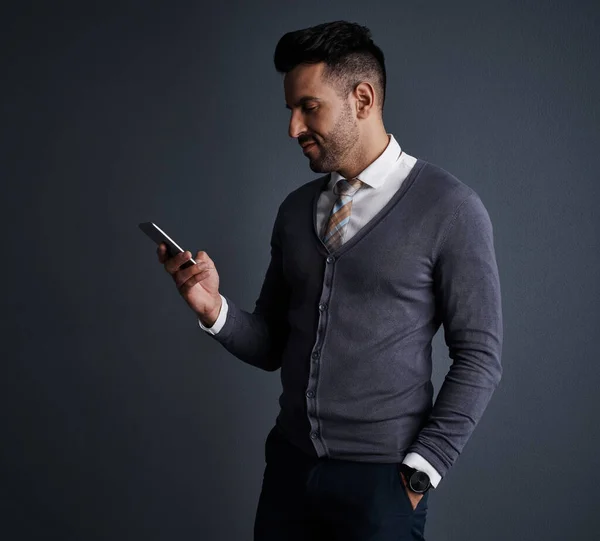 stock image The instant way to stay in touch. Studio shot of a stylish young businessman using a mobile phone against a gray background