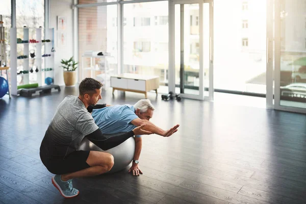 stock image His support his vital to his patients recovery. a young male physiotherapist assisting a senior patient in recovery