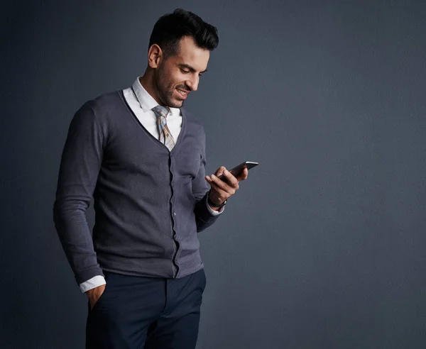 stock image Communicating with clients through mobile apps. Studio shot of a stylish young businessman using a mobile phone against a gray background