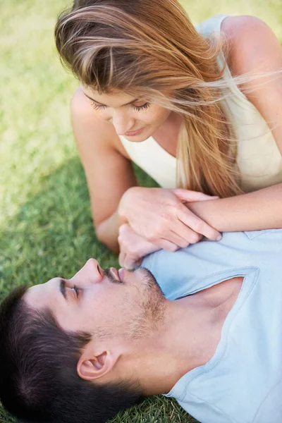 特別な視線を共有する 一緒に草の上に寝そべって笑っている魅力的な若いカップル — ストック写真