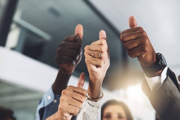 Well be here to offer all the encouragement you need. Closeup shot of a group of businesspeople showing thumbs up in an office