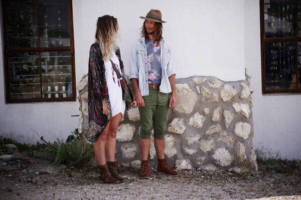 Just a couple of happy hippies. a trendy young couple standing together against the wall of a building outside