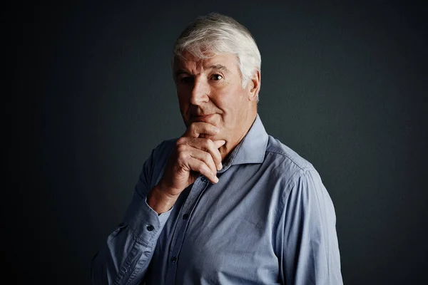 stock image I wonder...Studio shot of a handsome mature man looking thoughtful against a dark background