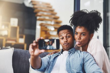 Birlikte oynayan çiftler birlikte kalır. Mutlu genç bir çift evdeki kanepede selfie çekiyor.