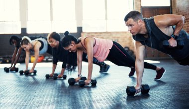 Daha çok çabalamak ve daha formda olmak. Spor salonundaki seanslarında dambıl kullanan bir fitness grubu.