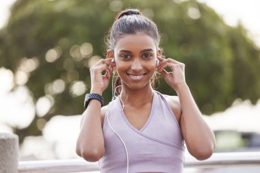 Fitness, parkta kulaklıkları olan mutlu bir kadının portresi. Egzersiz molası. Müzik ya da podcast dinliyor. Egzersiz, eğitim ve doğada koşarken radyo yayını için kulaklık takan kız..