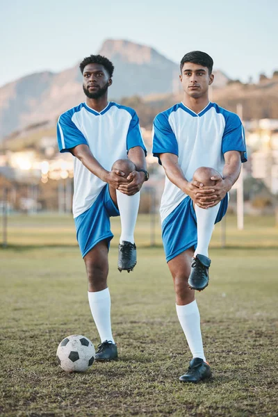 Football, team sports and stretching legs on field for fitness, exercise and training outdoor. Soccer ball, pitch and diversity athlete men together for sport competition, workout or muscle warm up.
