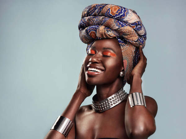 Beauty, black woman and smile with African head scarf and mockup in a studio. Isolated, blue background traditional Africa turban with a young female model with culture and pride with cosmetics.