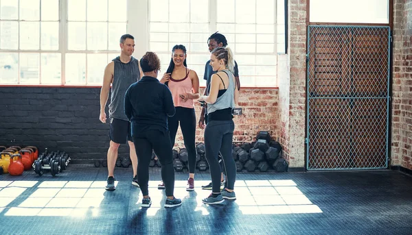 Some exercise discussions. a cheerful young group of people standing in a circle and having a conversation before a workout in a gym