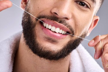 Yüz, erkek ve diş ipi, beyaz bir arka planda izole edilmiş stüdyo ortamında diş sağlığı için. Portre, diş ipi ve erkek model diş temizliği ağız sağlığı, hijyen ve taze nefes için sağlıklı diş etleri.