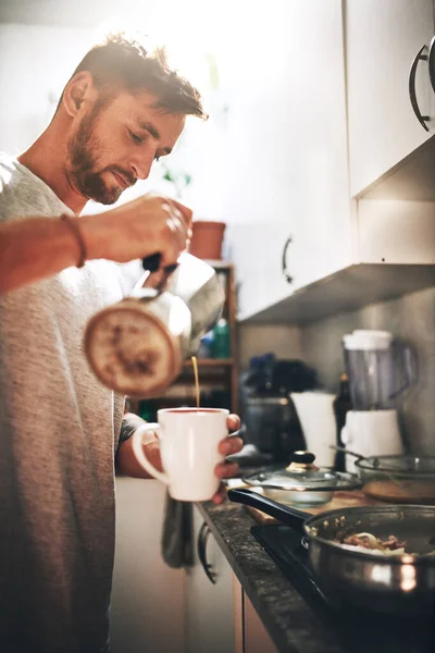 stock image Breakfast of champions. a cheerful young man pouring coffee into a cup inside of the kitchen at home