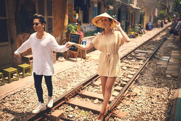 あなたの心を幸せにする何かを毎日しなさい ベトナムの街を電車の線路を歩いている若いカップルが — ストック写真