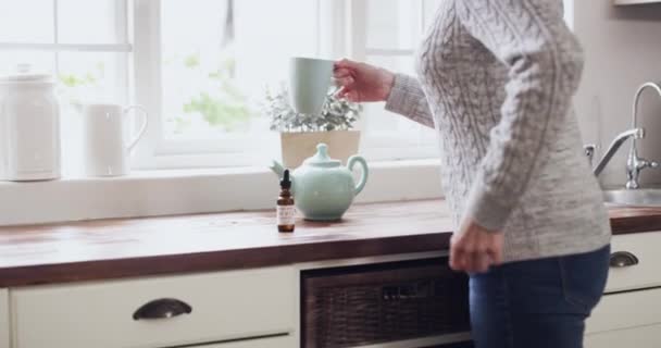 慢性疾患の治療のために彼女の家の台所で高齢者の女性とお茶 Cbd油と腰痛 女性年配の年金受給者が飲料を飲んでいる大麻 — ストック動画