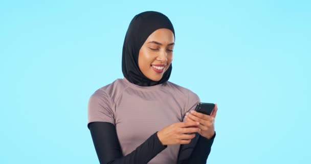 ソーシャルメディア モバイルアプリやインターネット上のスタジオネットワーク内の電話 幸せとイスラム教徒の女性 笑顔と青の背景によって隔離された携帯電話でオンラインで閲覧イスラム女性モデル — ストック動画