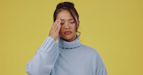 ストレスと頭の痛みに疲れて若いアジアの女性 頭痛やスタジオの背景 Z世代の女の子 学生と心の疲労に不満 燃え尽きと流行の服によって黄色の背景 — ストック動画