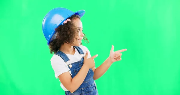 Children, construction worker and a girl on green screen background in studio pointing at building space. Kids, architecture or design with a cute female child engineer wearing a hardhat on chromakey.
