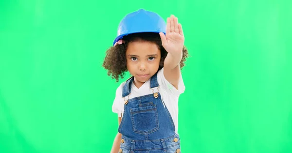 Stop, construction and face of a child on a green screen isolated on a studio background. Safety, security and portrait of a girl kid with a warning hand for building, renovation and maintenance.