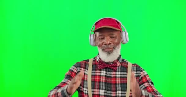 ダンス スタジオの緑の画面の背景にヘッドフォンを持つシニア黒人男性が楽しんでいます パーティー ファッション ファンキーで幸せな高齢者の男ダンスオンChromakey Mokupのために自由 — ストック動画