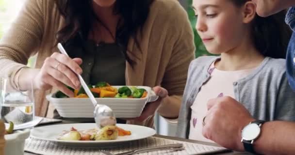 吃得健康 午饭时和家人一起吃饭 饿着肚子在屋里吃饭 快乐的谈话 父母在一起吃饭的时候和一个小女孩谈论蔬菜 — 图库视频影像