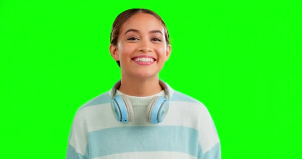 面白いと彼女の首の周りにヘッドフォンでスタジオで緑の画面の背景に女性 肖像画 笑顔とユーモア魅力的な若い女性と音楽を聴く上でChromakeyモックアップ — ストック動画