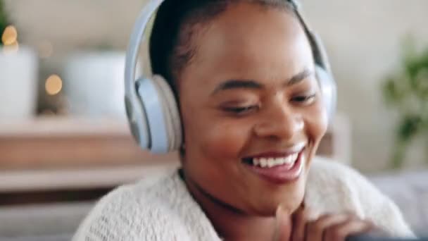 ヘッドフォン スマートフォン 黒人女性が踊り ソファと音で幸せ 音楽に耳を傾け リラックスしてください ダンス ナイジェリアの女性と女性のヘッドセット 携帯電話と笑顔でオーディオストリーミング — ストック動画