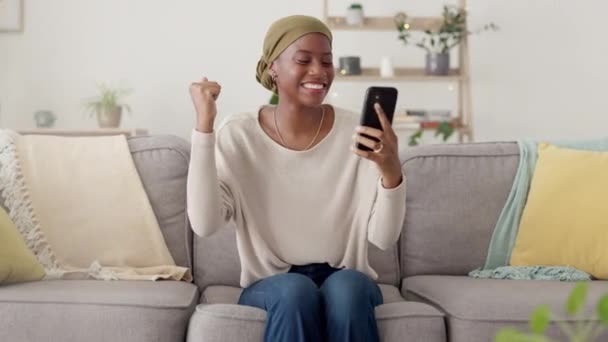 家庭でソファの上で幸せな黒人女性 電話や成功 良いニュースや仕事の機会の勝者 モバイルでボーナス契約 勝利または勝利賞を祝うために笑顔で興奮し すごいまたはアフリカの女性 — ストック動画