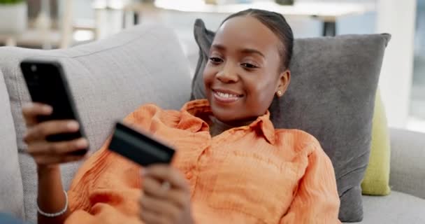 网上购物 电话或女孩与信用卡支付通过互联网或金融技术网站在家里 快乐的微笑 放松或黑人女性在沙发上通过数字或银行移动应用程序输入汇款 — 图库视频影像