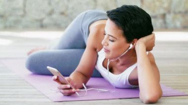 Yüz, telefon ve fitness kadını egzersiz, egzersiz ve mola için yoga minderinde müzik eşliğinde rahatlar. Sağlık eğitiminden sonra podcast, radyo ve ses yayınlanırken mutlu, portre ve kadın gülüşü.